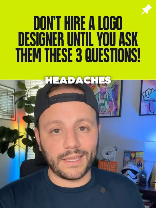 Greg wearing a backward black cap speaking in a room with colorful artwork and plants, with bold text above reading 'DON'T HIRE A LOGO DESIGNER UNTIL YOU ASK THEM THESE 3 QUESTIONS!' and the word 'HEADACHES' over his forehead.