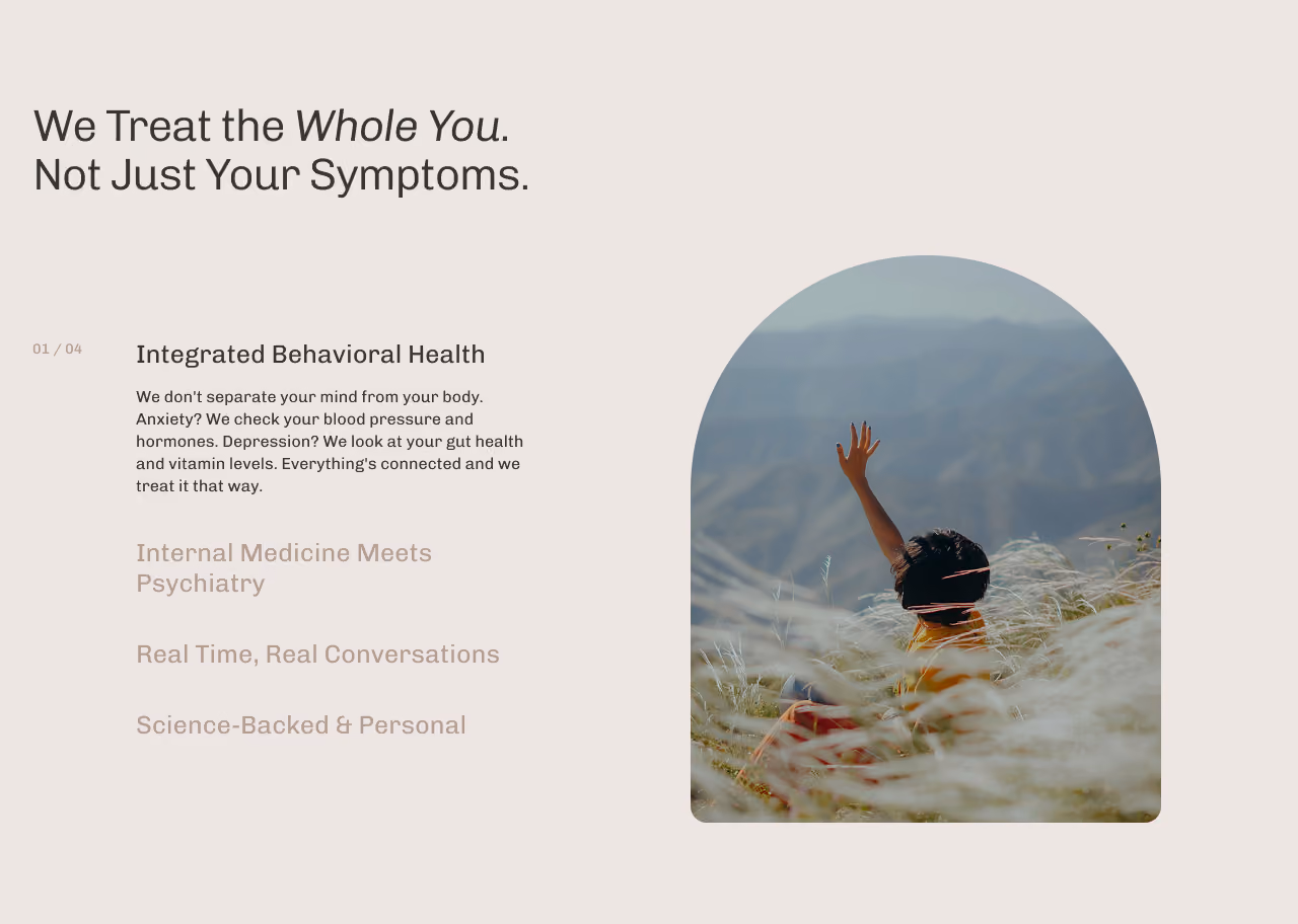 Text emphasizing treating the whole person, not just symptoms, with a focus on integrated behavioral health and connections between mind and body. To the right, a person sitting in tall grass on a hillside raises one hand, with a blurred mountainous landscape in the background.