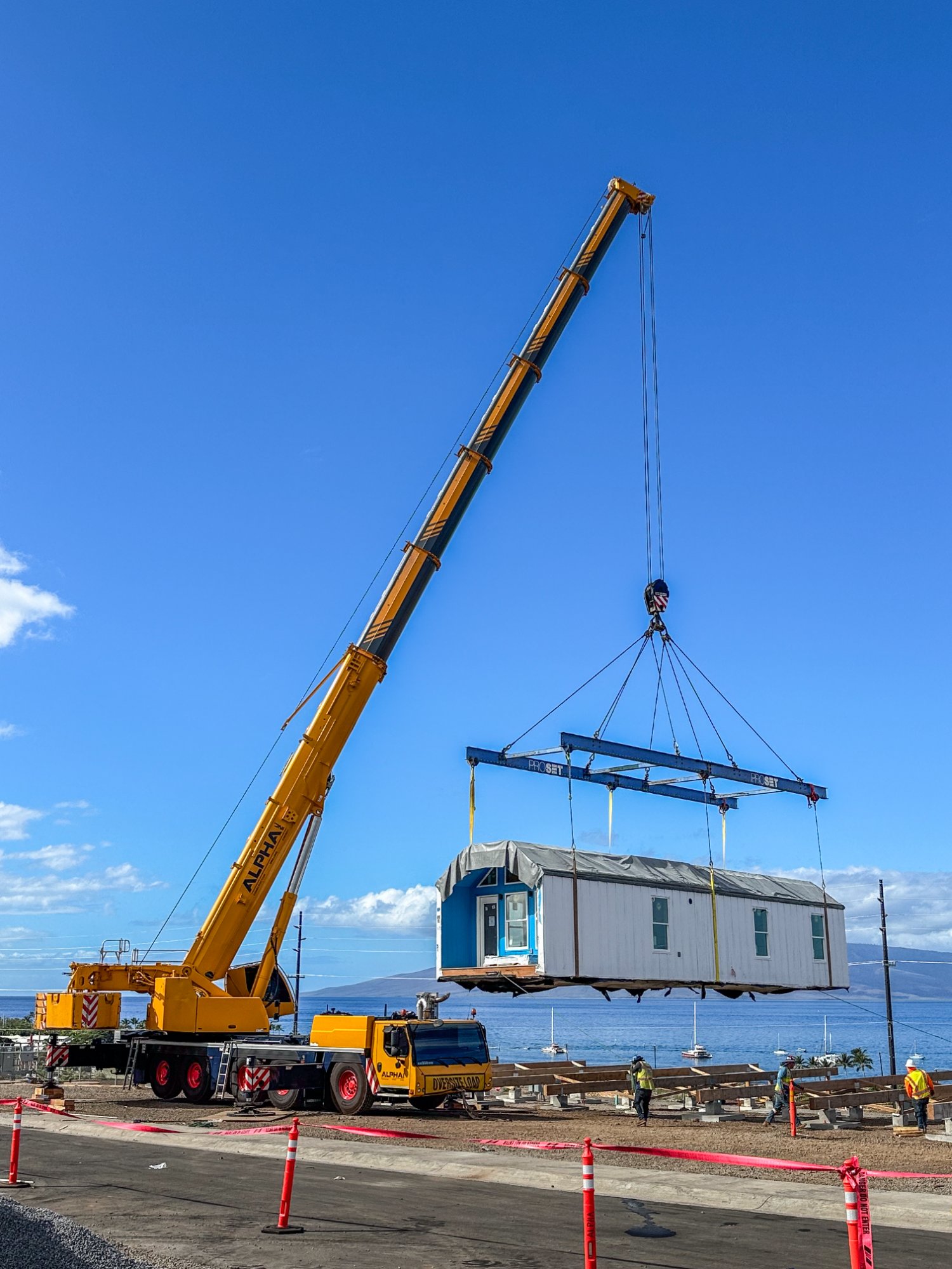 Crane setting a home on foundation in Maui