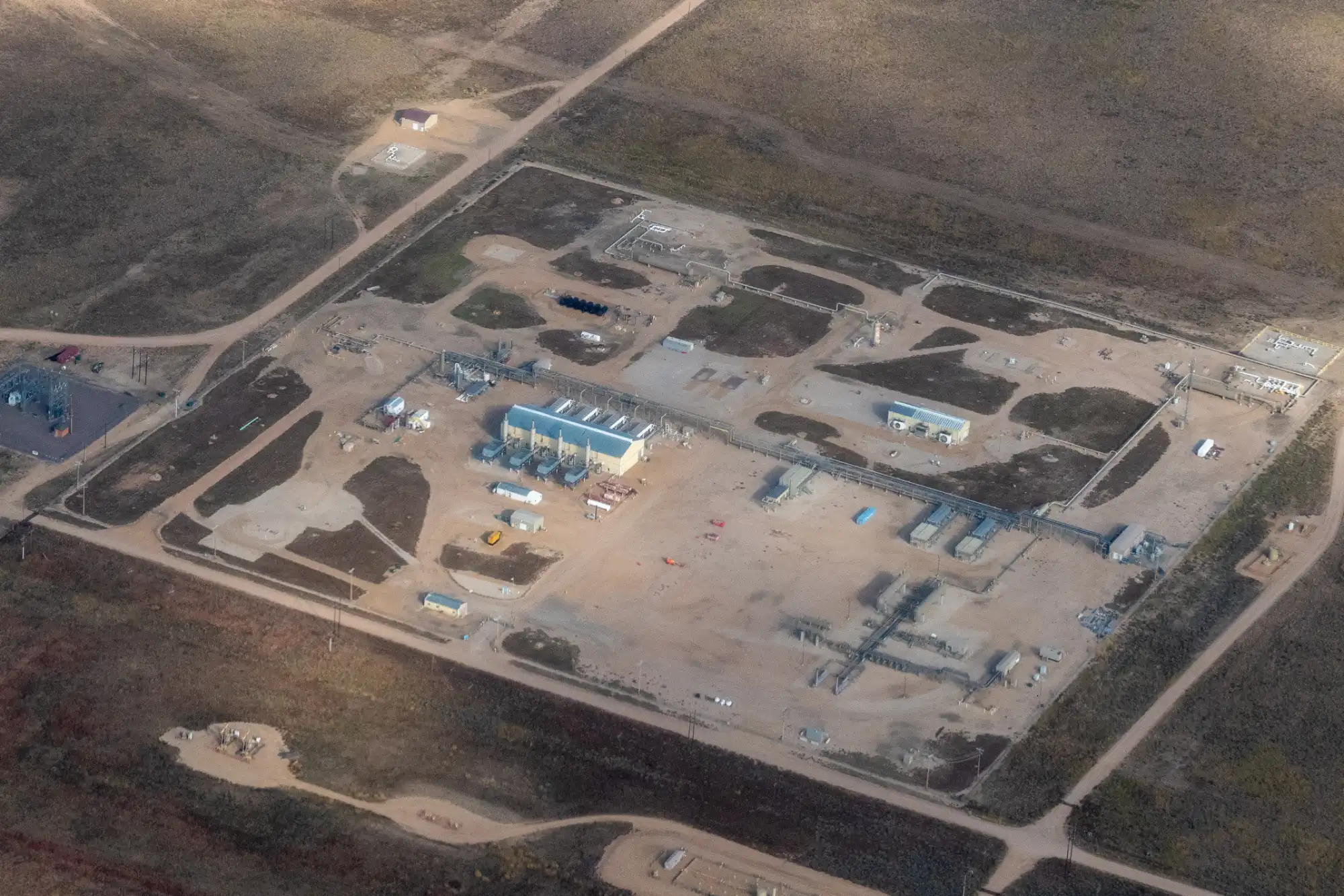 Aerial view of industrial site with interconnected yellow pipelines and colorful smoke plumes overlaid with radar-style circular grid and a wolf icon at the center.