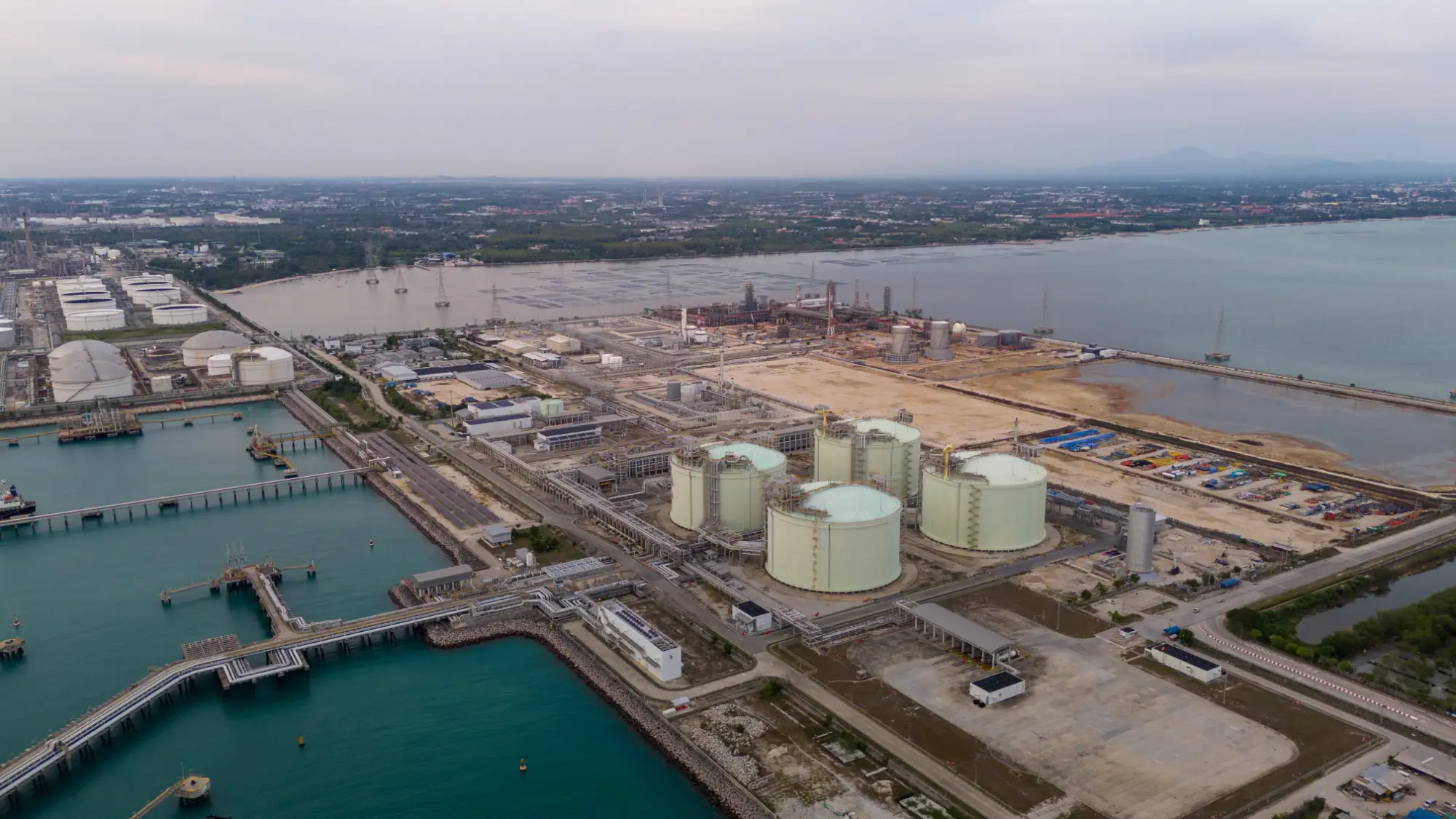 Aerial view of industrial site with interconnected yellow pipelines and colorful smoke plumes overlaid with radar-style circular grid and a wolf icon at the center.