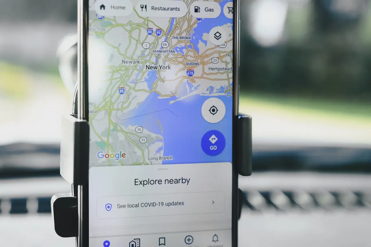 Smartphone in car mount showing Google Maps focused on New York with options to explore nearby places.