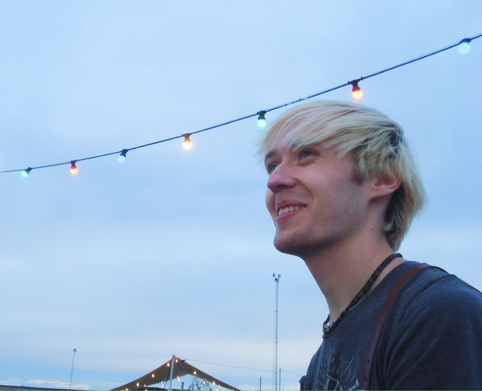 A picture of Trey Anderson under a string of colorful lights and an overcast sky.