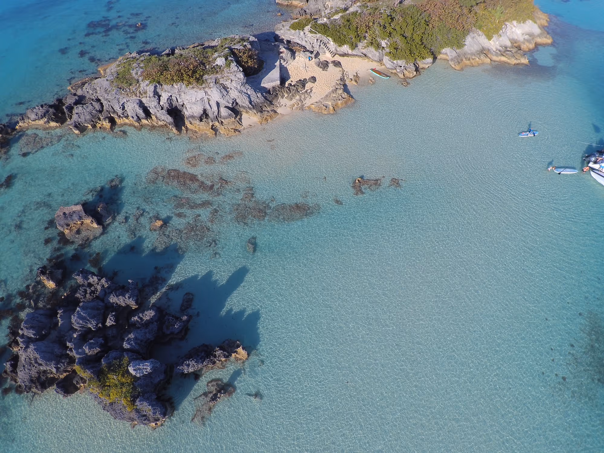 Aerial view of water with small beach and rocks