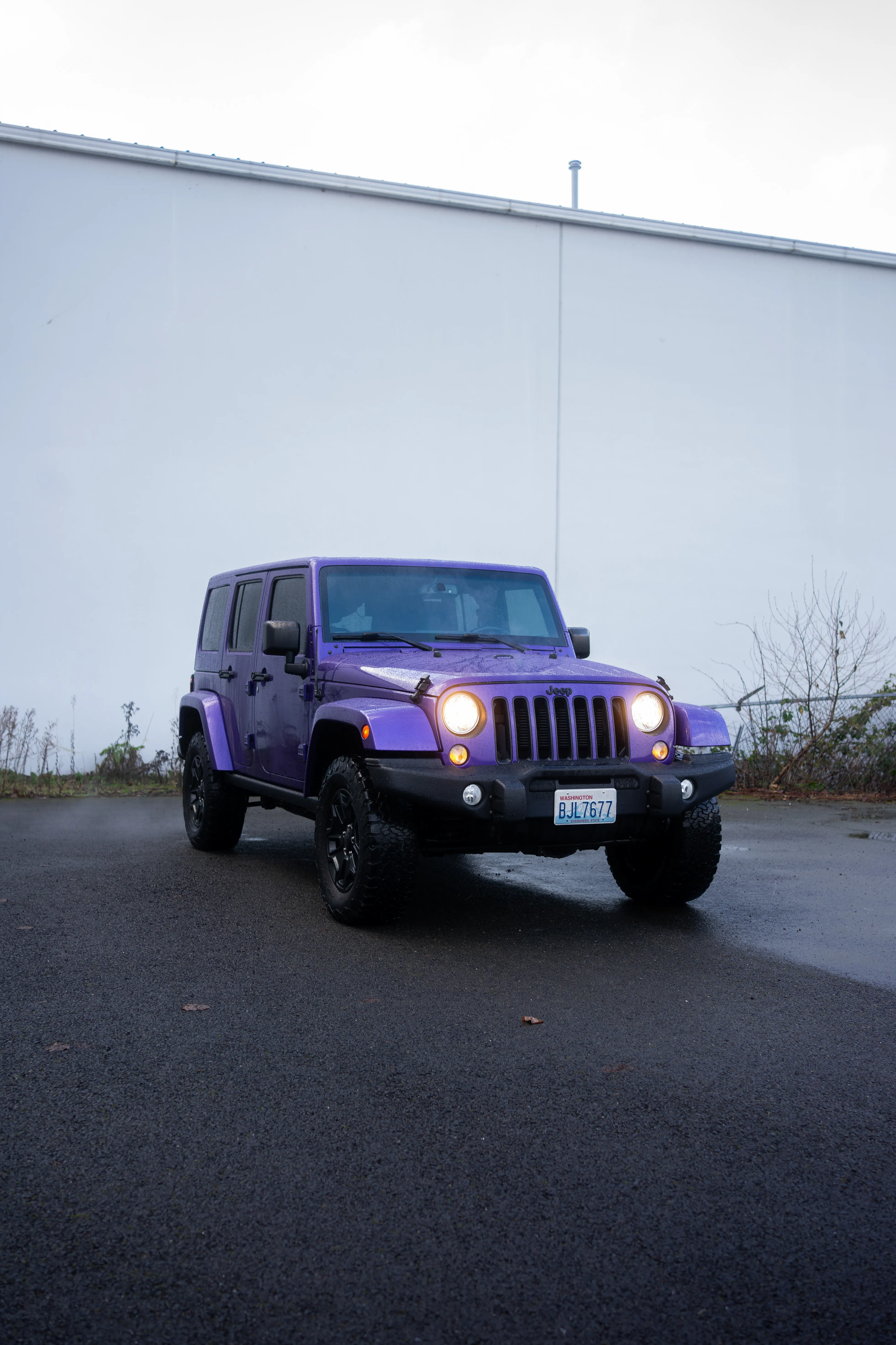 Purple Jeep Wrangler Unlimited with headlights on