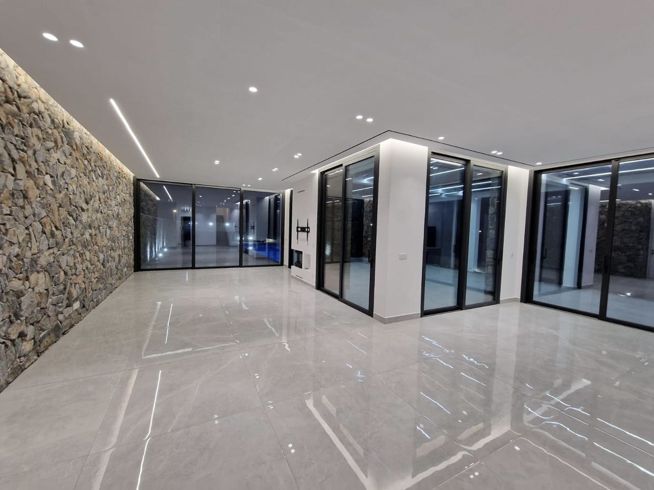 Open-plan ground floor with stone feature wall and sliding glass doors, Sea Caves villa, Paphos