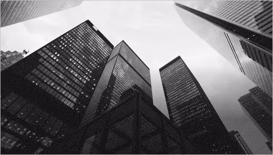 Black and white photo of tall skyscrapers viewed from street level looking up at the sky.