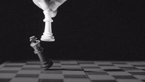 Hand holding a white king chess piece capturing a black king on a chessboard.