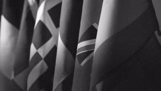Close-up of several national flags hanging side by side in grayscale.