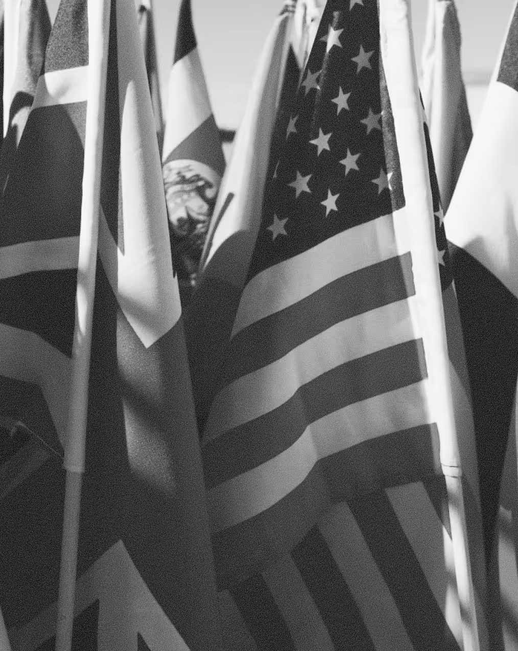 Multiple national flags including the United States flag grouped closely together indoors.