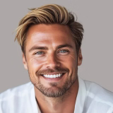 Smiling man with blond hair and beard wearing a white shirt against a plain background.