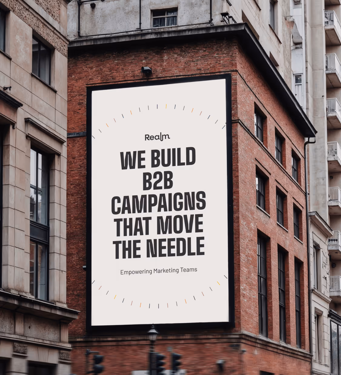 Large billboard on a brick building displaying 'Realm We build B2B campaigns that move the needle Empowering Marketing Teams.'
