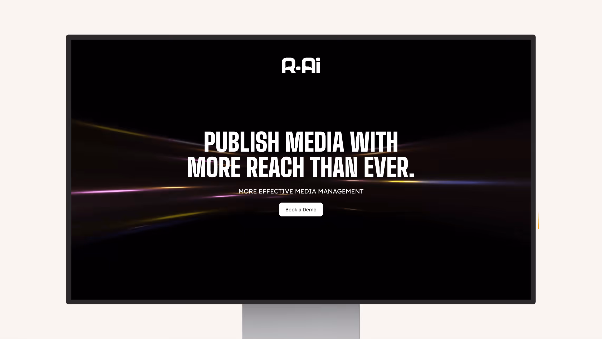 Computer monitor screen displaying R-Ai with text 'Publish media with more reach than ever' and a 'Book a Demo' button.