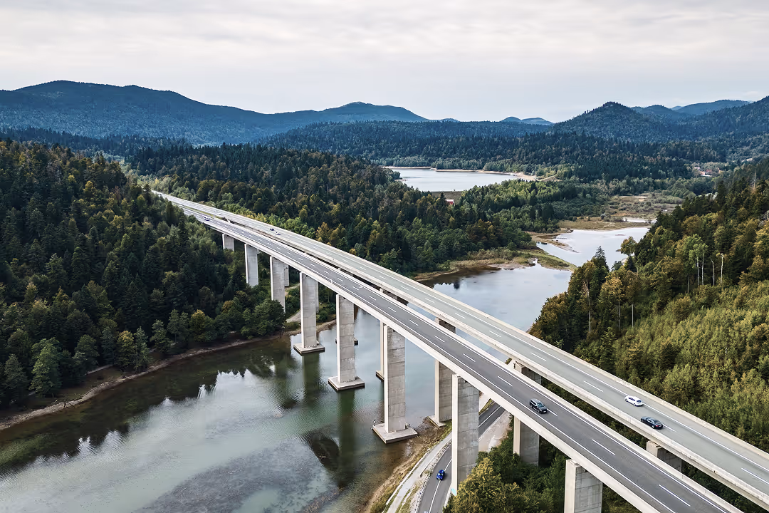 a bridge over a river with trees and mountains