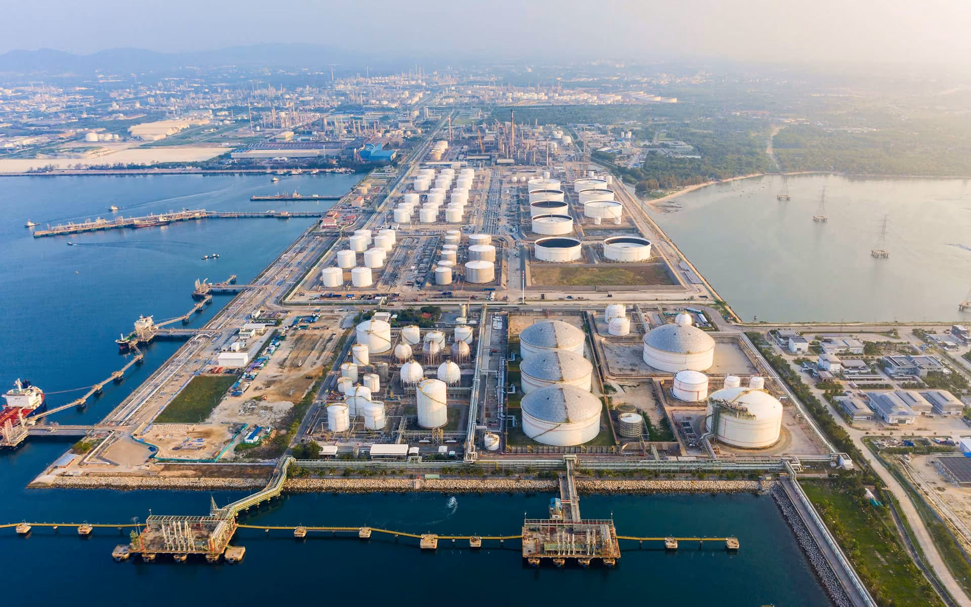 Aerial view of a large industrial oil refinery complex with storage tanks near the coastline.