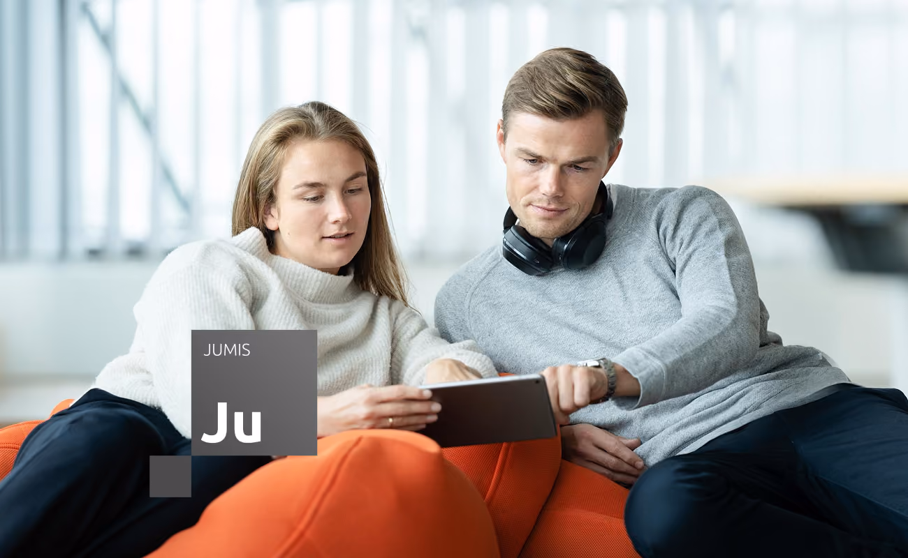 Divi kolēģi apspriež darba jautājumus, kopīgi skatoties informāciju planšetē.