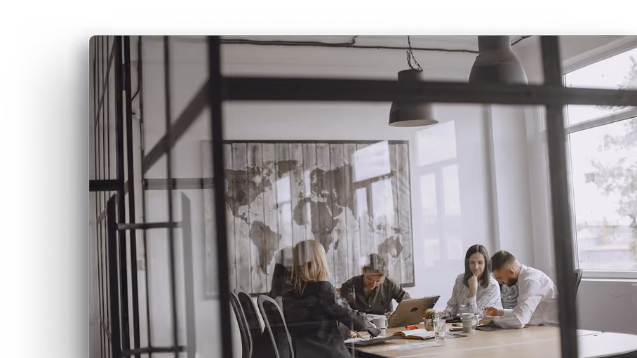 A team in a meeting working with computers and documents at a table.