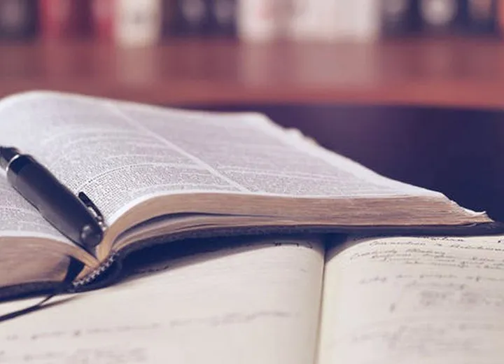 Miniature shopping cart placed on a laptop keyboard with a notebook and pen nearby, symbolizing online shopping.