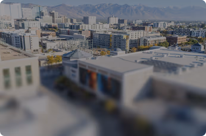 Cityscape with low and mid-rise buildings and mountains in the background.