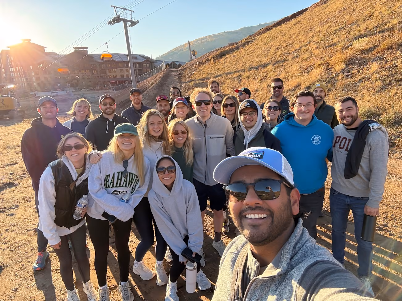 AirGarage team taking a group selfie on a mountain trail near a ski lift