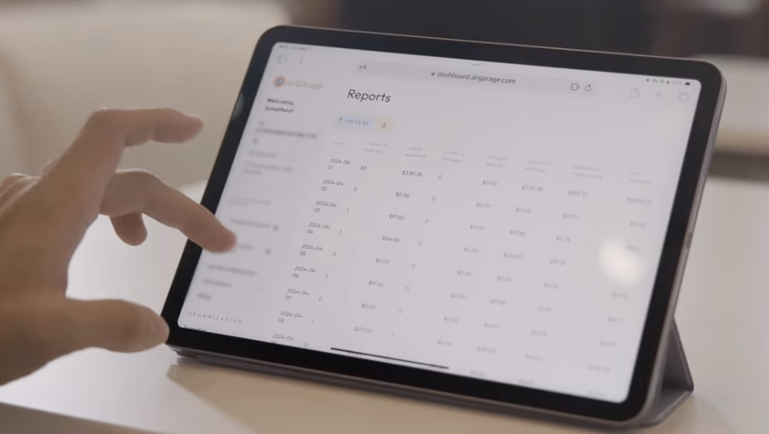 Hand navigating the AirGarage dashboard reports on a tablet screen