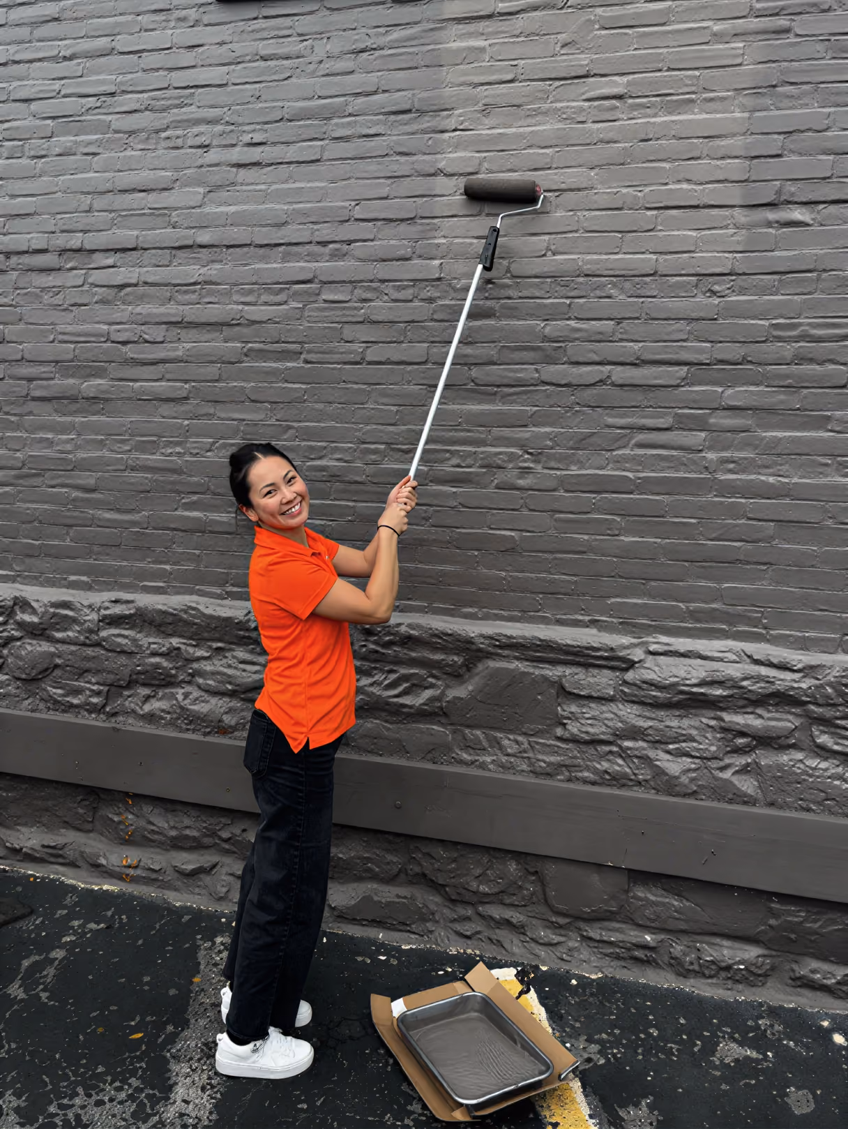 AirGarage team member painting a brick wall with a roller