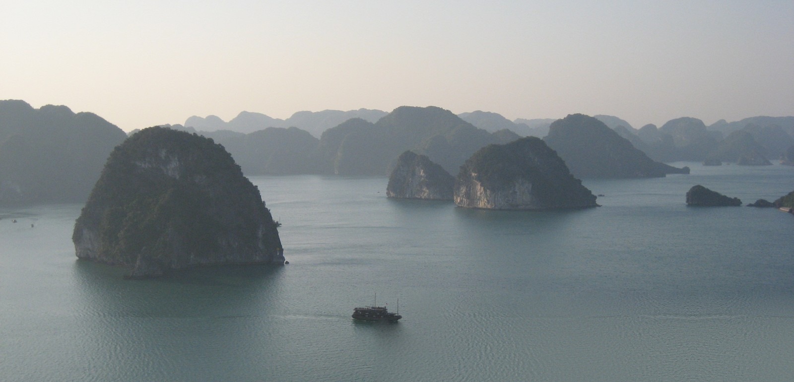 Ha Long Bay from a high viewpoint, with islands across the horizon and a ship on the water.