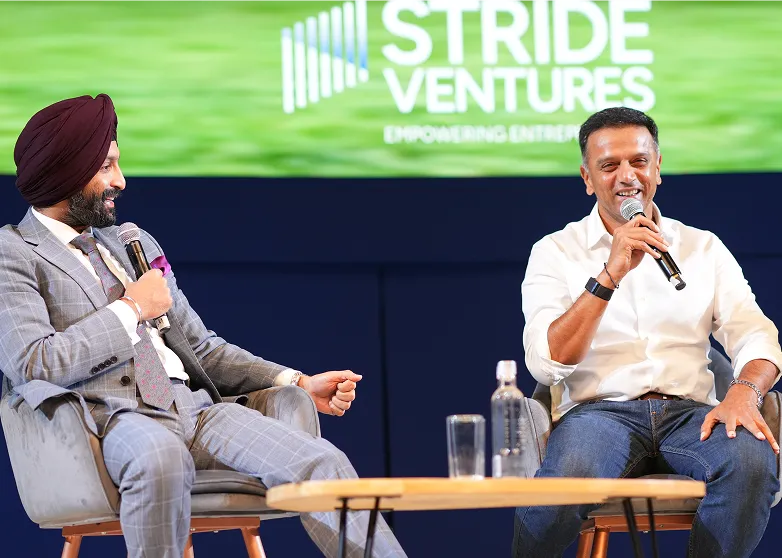 Two men seated and speaking into microphones on stage with a 'Stride Ventures' sign in the background.