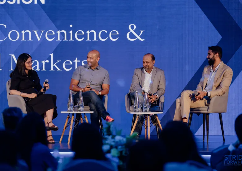 Four panelists seated on stage during a discussion with microphones and water bottles visible.