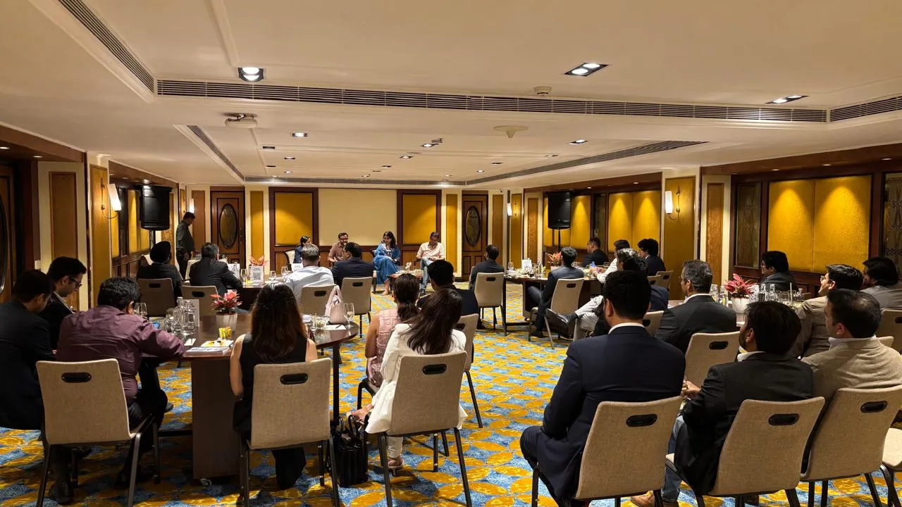 People seated in a conference room attending a formal meeting or panel discussion.