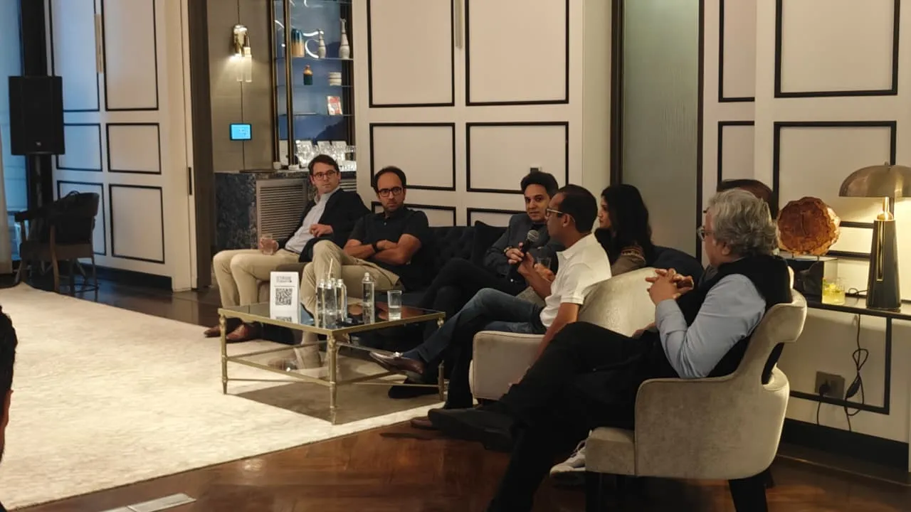 A group of people seated in a room, one man speaking into a microphone during a discussion.