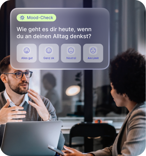Ein Mann und eine Frau unterhalten sich in einem Büro, während eine digitale Stimmungsabfrage mit den Optionen Alles gut, Ganz ok, Neutral und Am Limit eingeblendet wird.