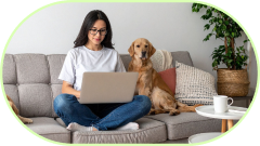 Frau sitzt mit Laptop auf dem Sofa neben einem Golden Retriever Hund.