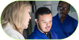 Drei Menschen in blauen und beigen Oberteilen, die zusammenarbeiten und auf ein Objekt oder Bildschirm schauen.