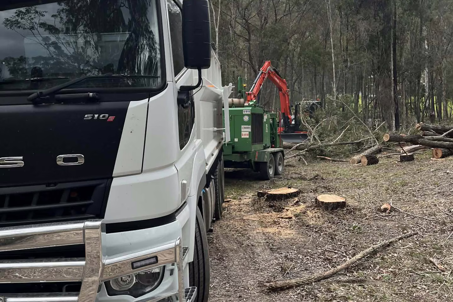 Tree service truck, chipper and excavator staged on site during a MidCoast bushland clearing job.