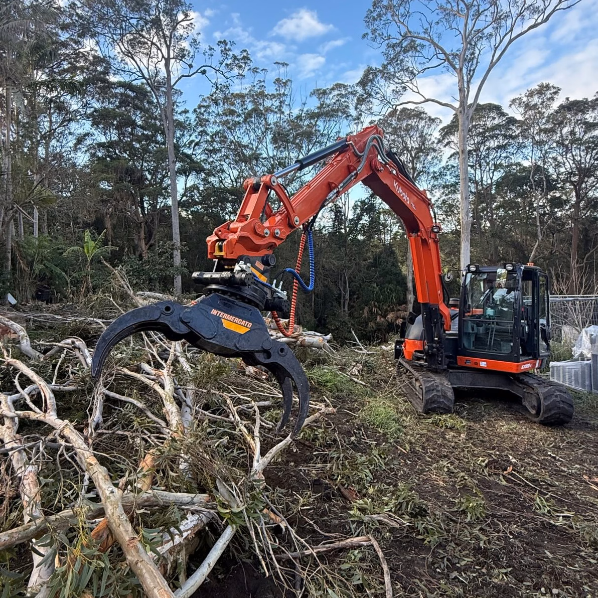 Excavator with grapple clearing overgrown scrub on a large bush block