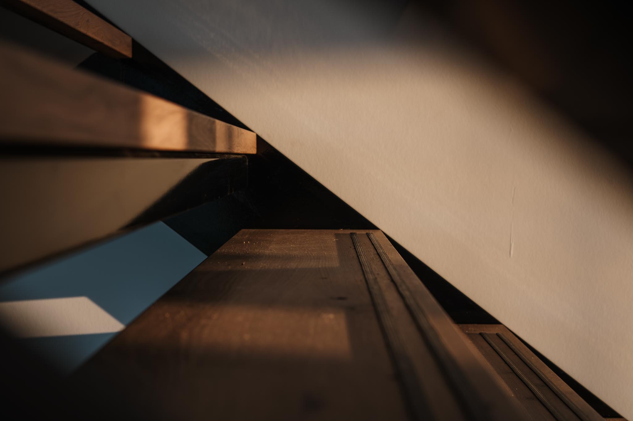 Close-up of wooden staircase steps with sunlight casting shadows on the wall.