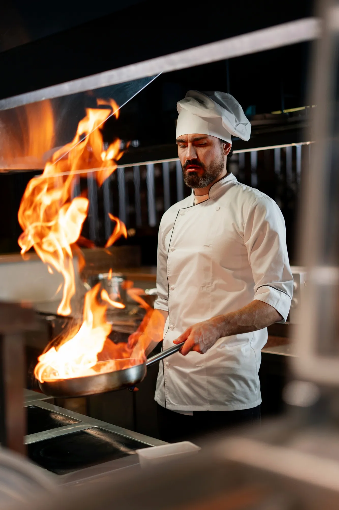 A chef is cooking on a grill with flames.