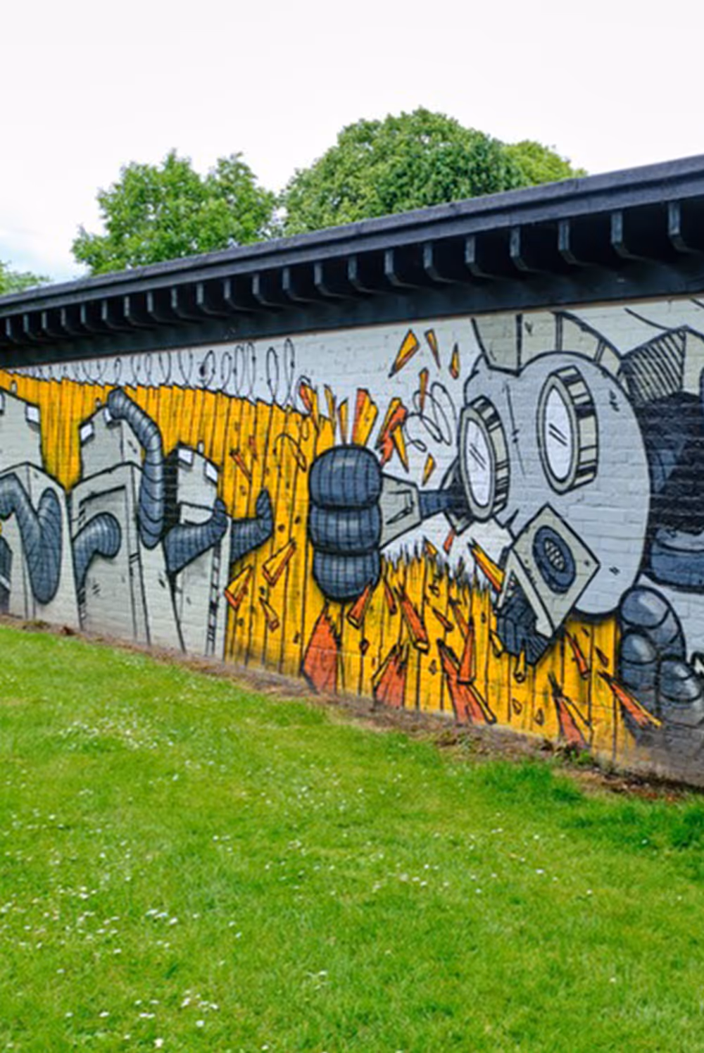 Street art of a large robotic figure with a gas mask and mechanical arm on a yellow and gray wall.