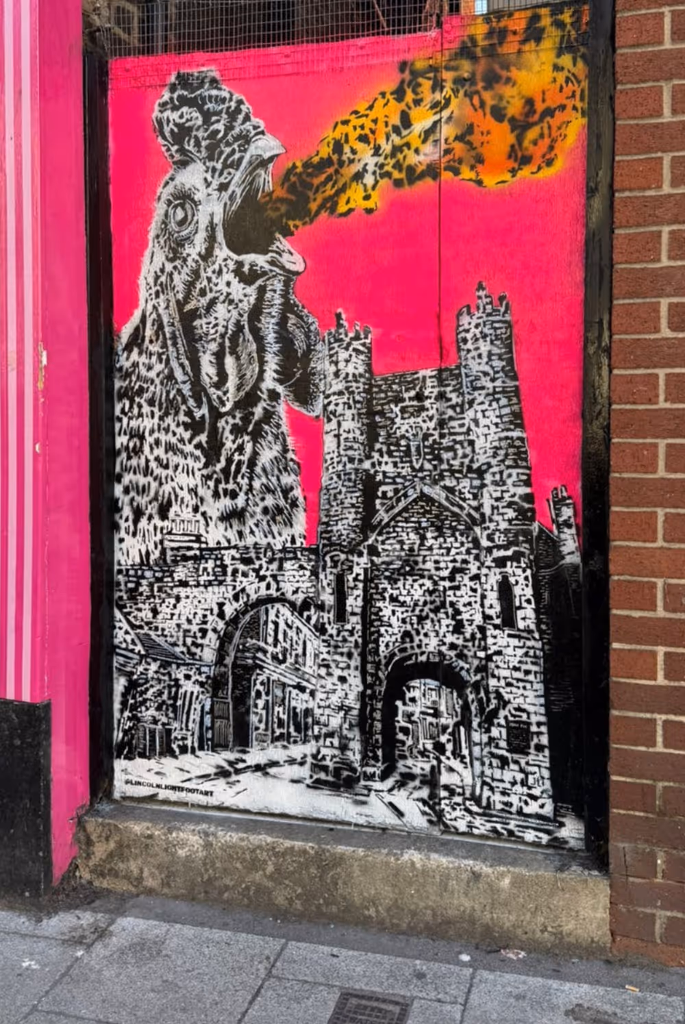 Street art of a roaring rooster breathing fire over a medieval stone castle on a bright pink background.