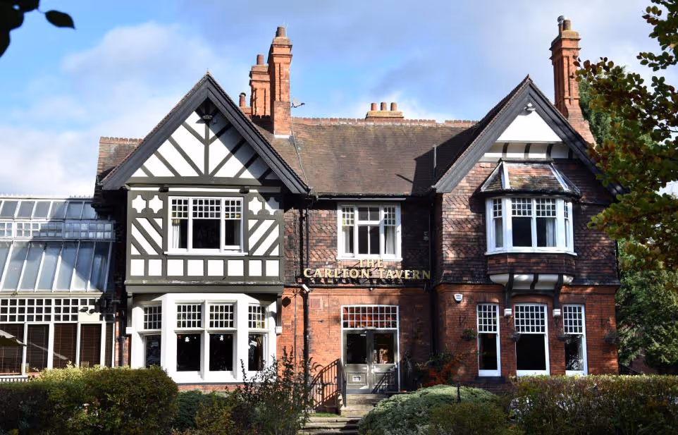 Facade of a traditional brick Tudor-style building with black and white timber framing and bay windows.
