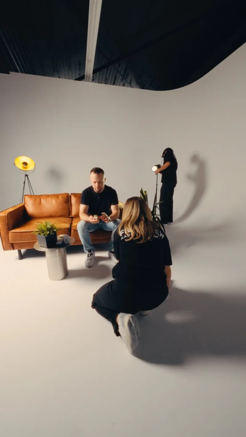 Interview-Szene im Hochformat, Crew kniet vor dem Sofa und gibt Anweisungen
