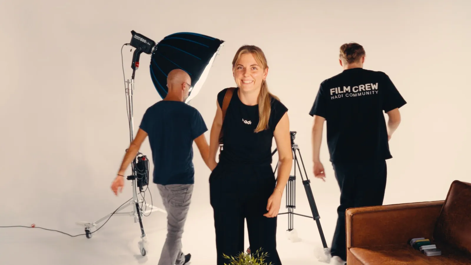 Lachendes Teammitglied von hadi am Set, im Hintergrund Softbox und Film Crew