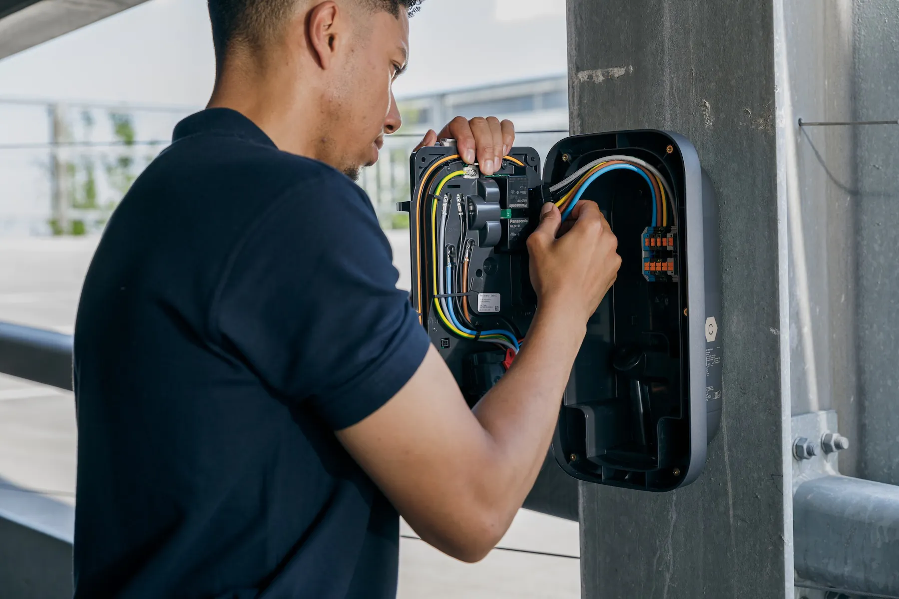 Technicus installeert of repareert bedrading in een elektrische kast aan een betonnen paal.