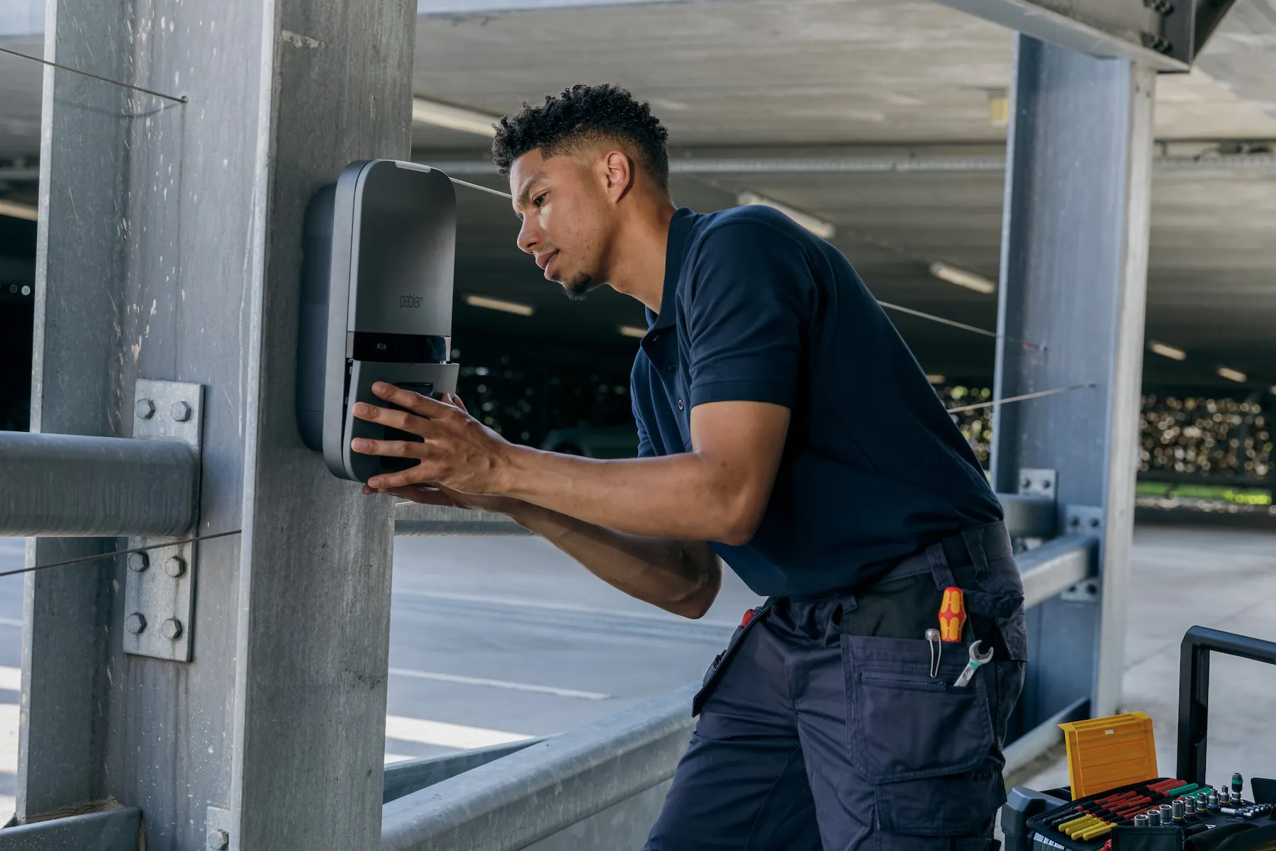 Technicus installeert een laadstation voor elektrische voertuigen in een parkeergarage.