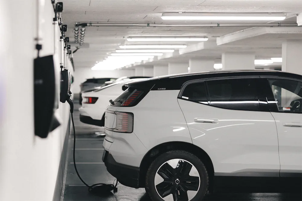 Witte elektrische auto die wordt opgeladen in een parkeergarage met meerdere oplaadpunten.