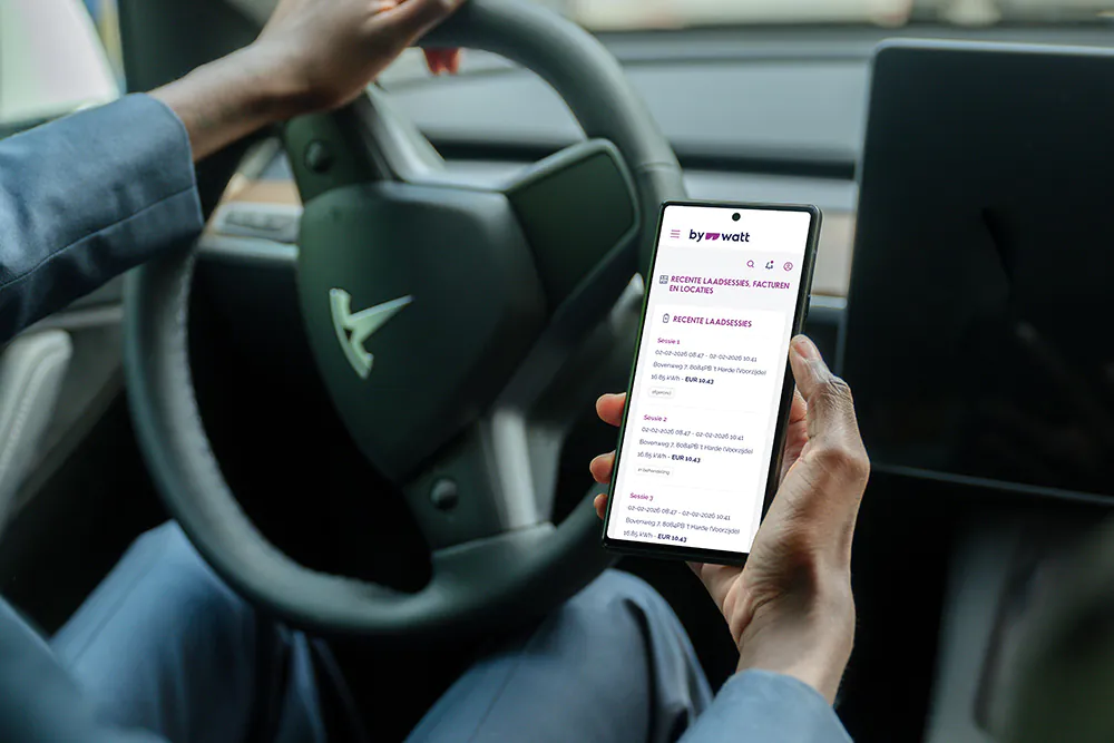 Persoon in auto kijkt op smartphone met laad- en factuurgegevens van byWatt-app.