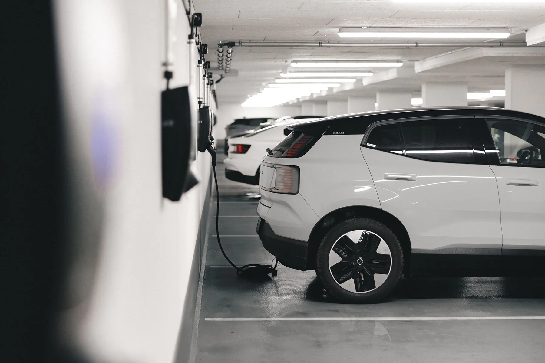 Parkeerplaats in garage met een elektrische auto die aan het opladen is aan de muur.