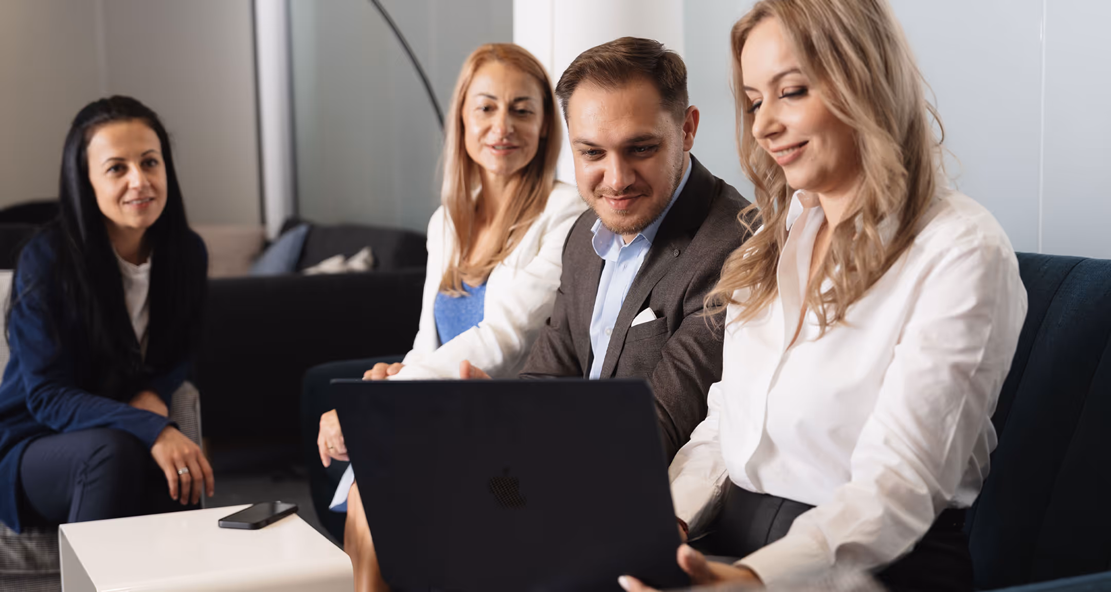 Four people in an office review invoice financing on a laptop in a professional setting.