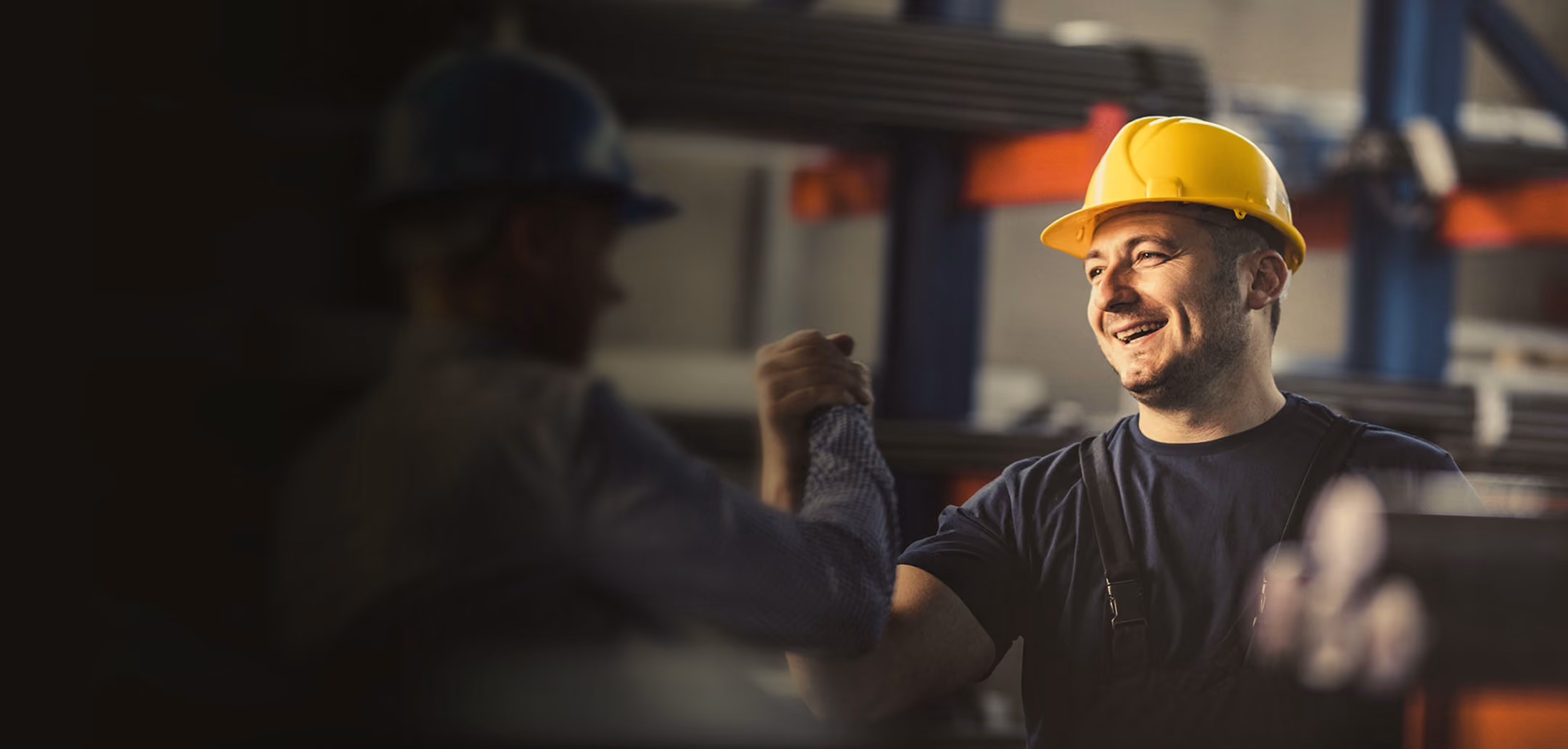 Dos trabajadores con casco se dan la mano en un entorno industrial, simbolizando liquidez para empresas.